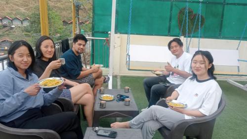 a group of people sitting in chairs eating food at Mountain view cottage in Rishīkesh