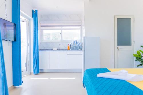 a white and blue bedroom with a bed and a window at Sea View Big Lanche in Praia Baixo