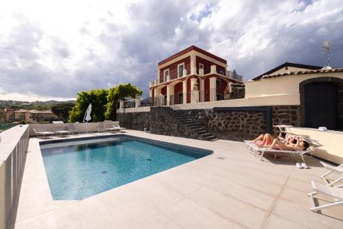 a house with a swimming pool and two people laying on chairs next to it at B&B Badimà in Fleri