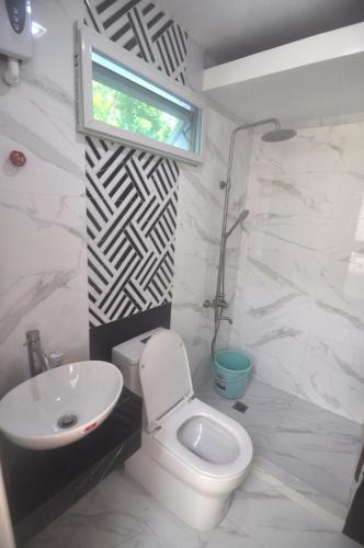 a bathroom with a toilet and a sink and a window at Aguada Hills Residence in Puerto Galera