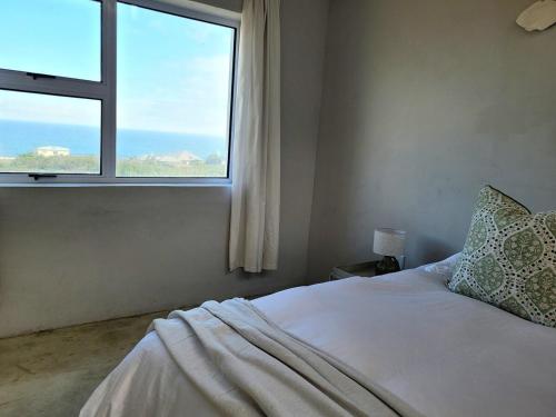 a bedroom with a bed and a large window at Silvertree Collective Ocean and Mountain View in Bettyʼs Bay