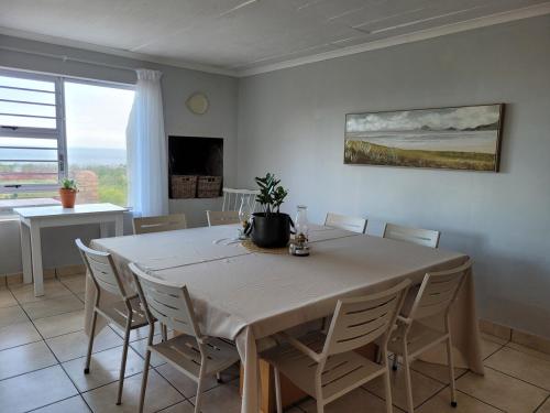 a dining room with a white table and chairs at Silvertree Collective Ocean and Mountain View in Bettyʼs Bay