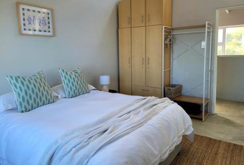 a bedroom with a large white bed with blue pillows at Silvertree Collective Ocean and Mountain View in Bettyʼs Bay