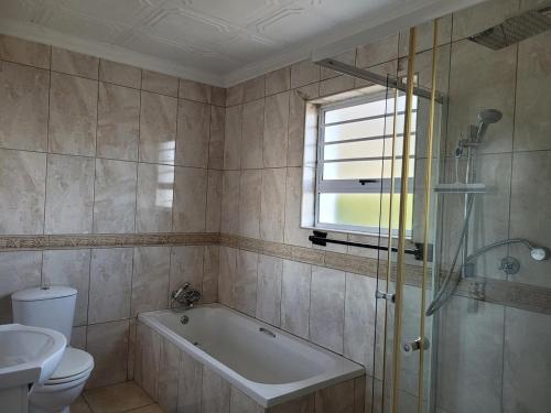 a bathroom with a tub and a toilet and a sink at Silvertree Collective Ocean and Mountain View in Bettyʼs Bay