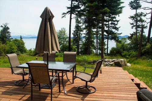 a table and chairs on a wooden deck with an umbrella at TideAway Farm on Private Island! Escape & Indulge Mother Nature! in Anacortes