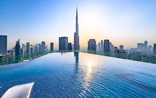 a infinity pool with a city skyline in the background at PARAMOUNT MIDTOWN RESIDENCES - A Luxury 2 BR Apartment near BURJ KHALIFA and DUBAI MALL in Dubai