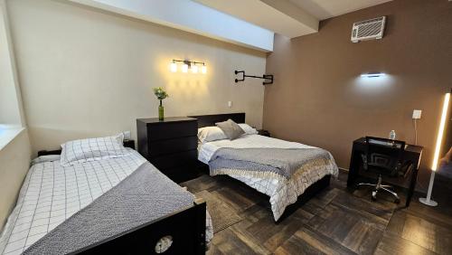 a bedroom with two beds and a television in it at A27 SUITE BLACK PLUS para 1 a 3 personas ESPECIALISTAS EN CORTAS, MEDIANAS Y LARGAS ESTANCIAS IZCALLI perfecto para Familias, Turistas, Contratistas, Estudiantes, Empresas y Ejecutivos A sólo 5 min Izcalli 15 min Esmeralda 20 min Satélite 25 min AIFA in Cuautitlán Izcalli