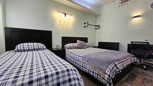 a bedroom with two beds and a chair at A27 SUITE BLACK PLUS para 1 a 3 personas ESPECIALISTAS EN CORTAS, MEDIANAS Y LARGAS ESTANCIAS IZCALLI perfecto para Familias, Turistas, Contratistas, Estudiantes, Empresas y Ejecutivos A sólo 5 min Izcalli 15 min Esmeralda 20 min Satélite 25 min AIFA in Cuautitlán Izcalli