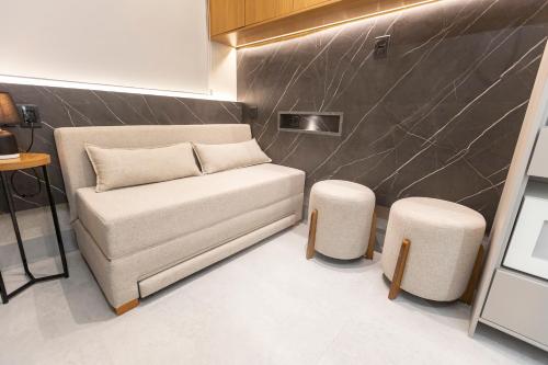 a living room with a couch and two stools at Arpoar Flat 118 - De frente para o mar in João Pessoa