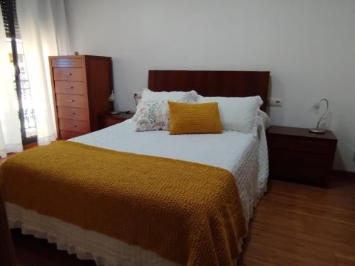a bed with an orange blanket and pillows on it at Apartamento A Cañiza in La Cañiza
