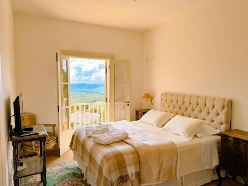 a bedroom with a large bed and a window at Villa Coração Guesthouse by Concavus in Monte Verde