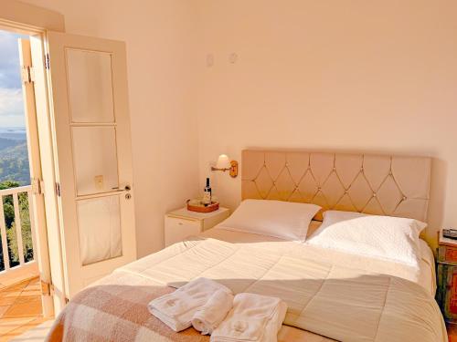 a bedroom with a large bed and a balcony at Villa Coração Guesthouse by Concavus in Monte Verde