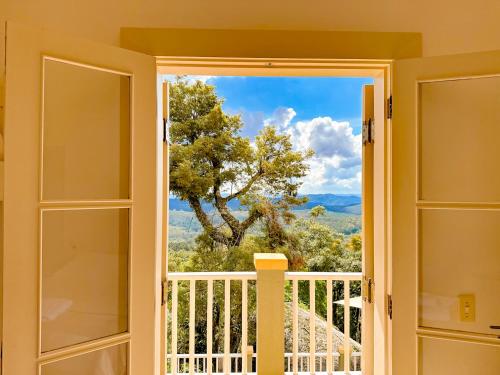 a door to a balcony with a view of a tree at Villa Coração Guesthouse by Concavus in Monte Verde