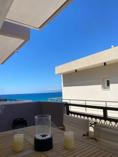 a table on a balcony with a view of the ocean at ARTEMIS beach studios in Kalamaki Heraklion