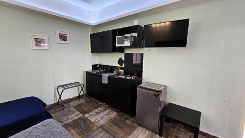 a small room with a small kitchen with a microwave at A21 SUITE BLACK MAX para 1 a 4 personas, Especialistas en CORTAS, MEDIANAS Y LARGAS ESTANCIAS en IZCALLI TEPOTZOTLAN perfecto para Familias, Turistas, Contratistas, Estudiantes, Empresas A sólo 5 min Izcalli 5 min Esmeralda 20 min Satélite 25 min AIFA in Cuautitlán Izcalli