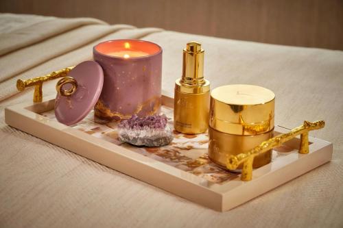 a tray with a candle and other items on a bed at The Ritz-Carlton Hotel de la Paix, Geneva in Geneva