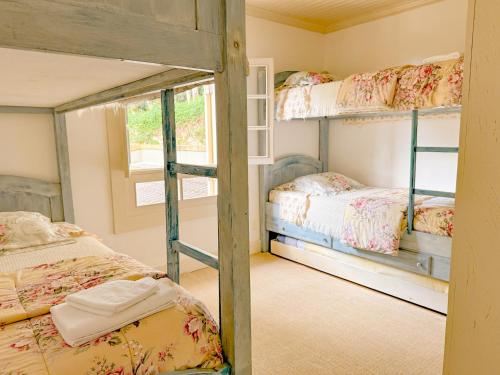 a bedroom with two bunk beds and a window at Villa Coração Guesthouse by Concavus in Monte Verde
