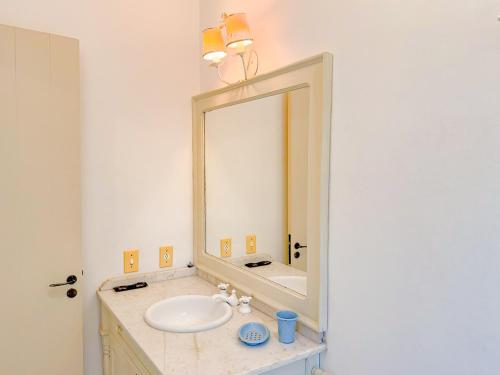 a bathroom with a sink and a large mirror at Villa Coração Guesthouse by Concavus in Monte Verde