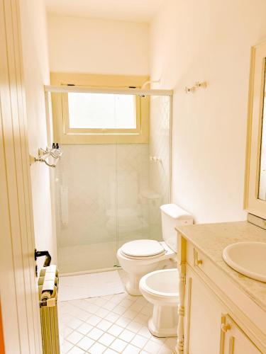 a bathroom with a toilet and a glass shower at Villa Coração Guesthouse by Concavus in Monte Verde