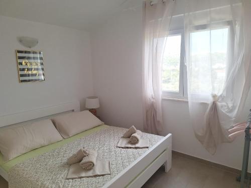 a white bedroom with a bed and a window at Apartmani AS in Jezera