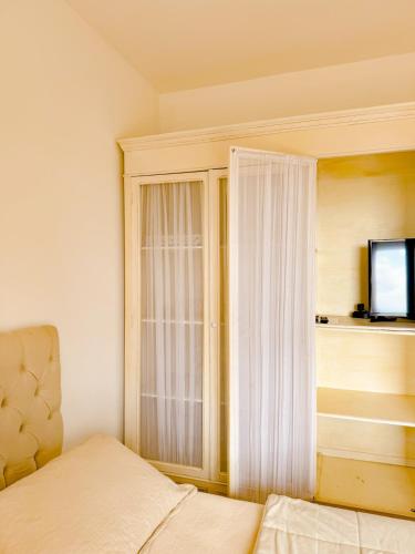 a bedroom with a bed and a window with a television at Villa Coração Guesthouse by Concavus in Monte Verde