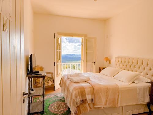 a bedroom with a large bed and a balcony at Villa Coração Guesthouse by Concavus in Monte Verde