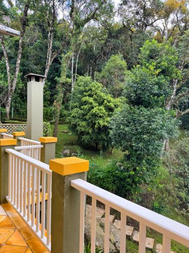 a white railing on a porch with a view of a garden at Villa Coração Guesthouse by Concavus in Monte Verde