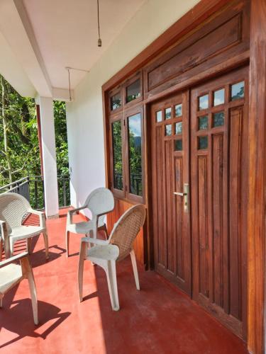 a porch with chairs and tables and doors at Silvil Homestay in Bandarawela