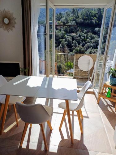 une table blanche et des chaises dans une pièce avec une fenêtre dans l'établissement JOLI 2 PIECES SERRIERA, à Serriera
