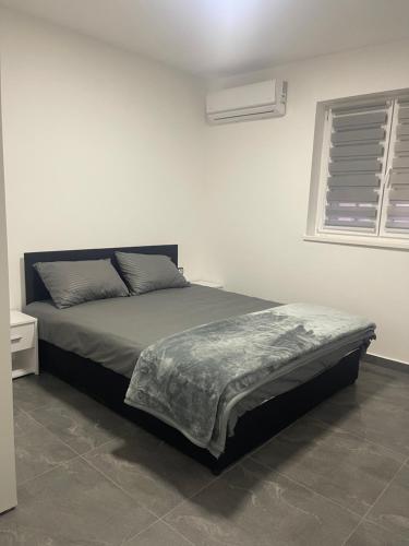 a bed in a white bedroom with a window at Vila Mila Ćirić in Pančevo