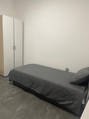a bed in a room with a white wall at Vila Mila Ćirić in Pančevo