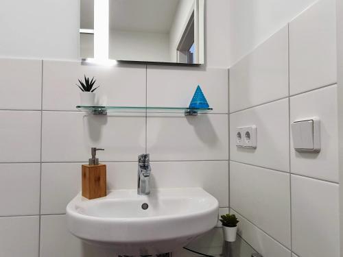 a white bathroom with a sink and a blue boat on the wall at Hogulu - klein und fein in der Altstadt, Appartement 10 in Brandenburg an der Havel