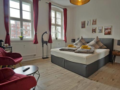 een slaapkamer met een bed en twee stoelen bij Hogulu - STILVOLL UND ZENTRAL - 3-RAUM Appartement 1 in Brandenburg an der Havel