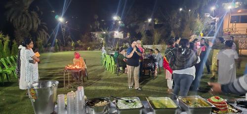 un gruppo di persone che si trovano intorno a un tavolo con cibo di Farm Stay Mount Abu a Mount Ābu