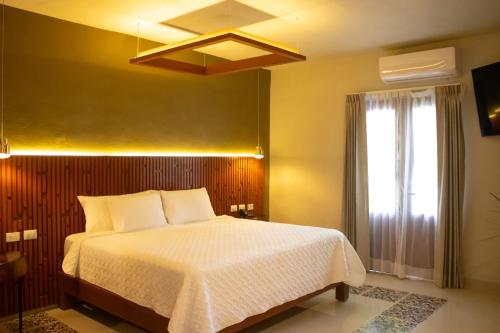 a bedroom with a white bed and a window at Hotel Poquito a Poquito in Valladolid