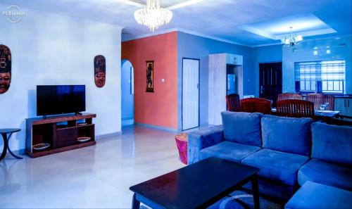 a living room with a blue couch and a tv at Sweet Retreat in Lusaka