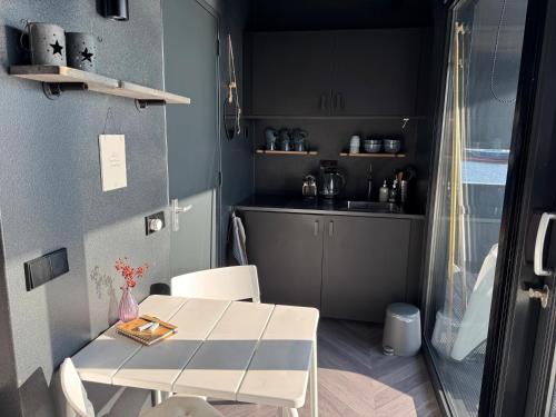 eine kleine Küche mit einem weißen Tisch und einer Theke in der Unterkunft Wohnboot 'TinyFloat' in Andijk IJsselmeer in Andijk