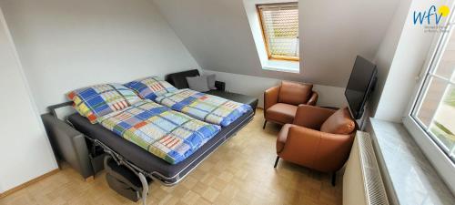Un pequeño dormitorio con una cama y una silla. en Fuhrmannshof Ferienwohnung Amke, en Juist