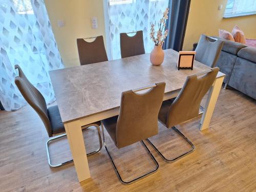a dining room table with chairs and a vase on it at Neue Ferienwohnung auf dem Land in Boppard