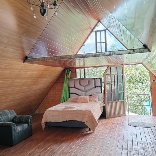 a bedroom with a bed and a large window at Cabaña Campestre Las Marías in Paipa