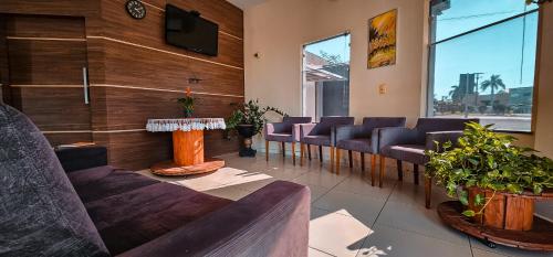 a waiting room with purple chairs and a flat screen tv at Hotel Parati in Parapuã