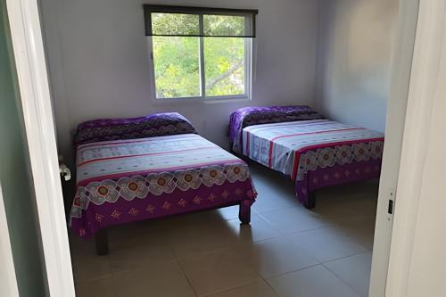 two beds in a room with a window at C7A Casas la colmena a 3 min playa alberca 3 rec. in Peñita de Jaltemba