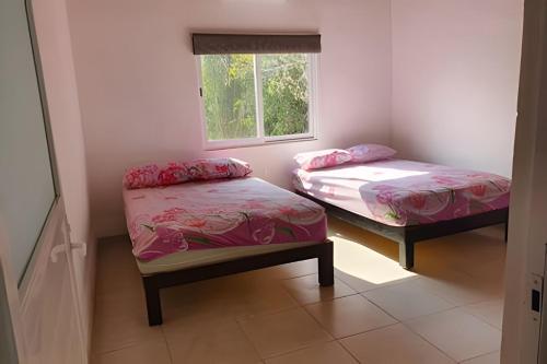 two twin beds in a room with a window at C7A Casas la colmena a 3 min playa alberca 3 rec. in Peñita de Jaltemba