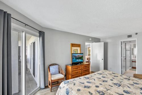 a bedroom with a bed and a tv and a window at Beach Club 327 in East End