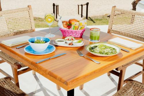 a wooden table with food and a glass of wine at Camino Real Zaashila Huatulco in Santa Cruz Huatulco