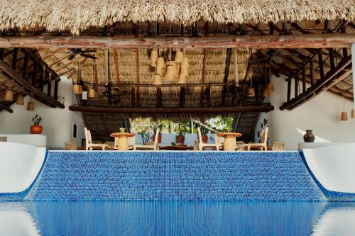 a swimming pool in a resort with a thatched roof at Camino Real Zaashila Huatulco in Santa Cruz Huatulco