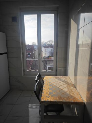 une table et une chaise dans une chambre avec fenêtre dans l'établissement Le Anatole, à Aubervilliers