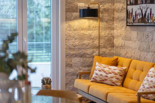 a yellow couch in a living room with a brick wall at 42° North Apartments in Tivat