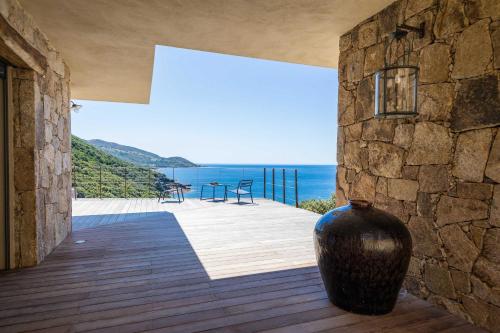 un grand vase assis sur une terrasse avec vue sur l'océan dans l'établissement Villa d'architecte - Piscine - Vue mer, à Calcatoggio