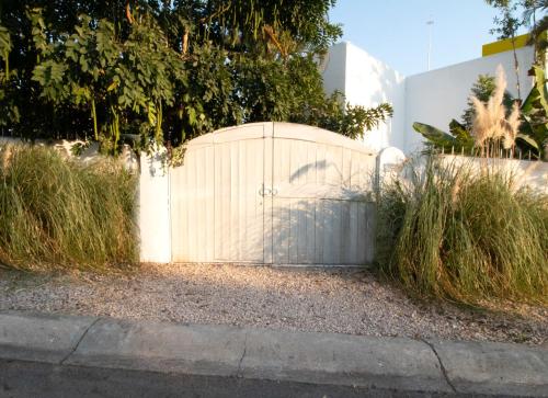 a white fence with a gate and some grass at Casita Perla Sustainable Villa with Mountain View, Long Pool, King, Grill in Texcalpan
